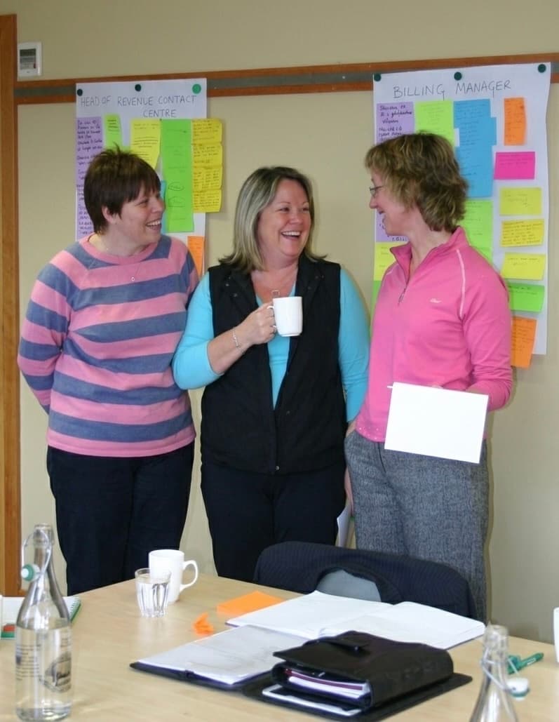 Three colleagues sharing a relaxed moment during a leadership working session